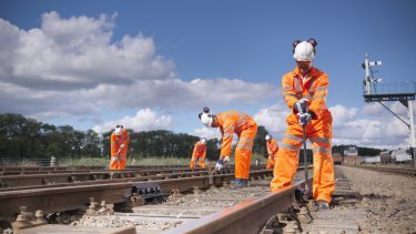 Railway workers wearing high visibility clothing repairing railway track