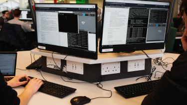 Two computer screens showing code and a virtual environment for programming robots