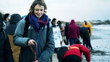 Female PGR student holding a spade on a geography field trip