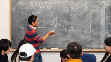 A maths lecturer at a blackboard