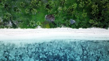 An aerial beach shot of a tropical beach with turquoise water in Fiji islands