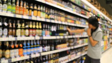 A stock image of a person browsing the alcohol aisle in a supermarket.