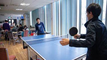 Two students play table tennis in the ELTC common room