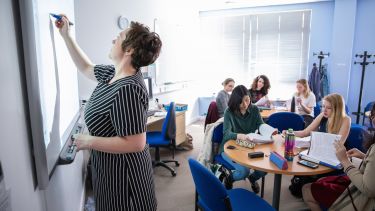 Teacher writing on interactive whiteboard in classroom