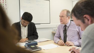 Tutor sits with students