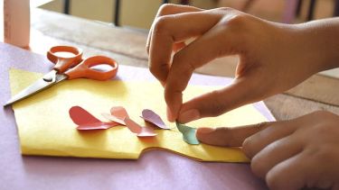 Child cutting paper to make cards