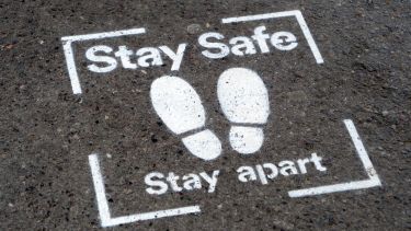 A 'Stay safe, stay apart' notice on the ground
