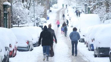 People walking along a road in heavy snow