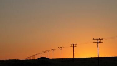 electricity power poles in a line against a sunset