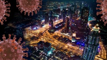 A modern city at night viewed from above, with images of viral molecules over the top