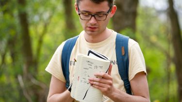 A student writes in a notebook on an urban exploration field class