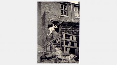 Children play in urban rubble in a vintage photograph from Hillfields