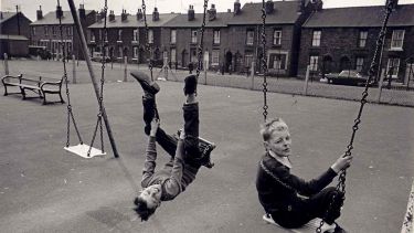 Children play on swings in a vintage photograph from Hillfields