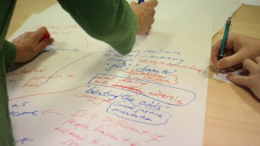 A close up of hands writing notes in a workshop