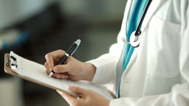 A photo showing a doctor writing on a clipboard