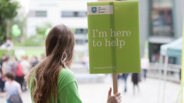 A volunteer student holds a sign offering help