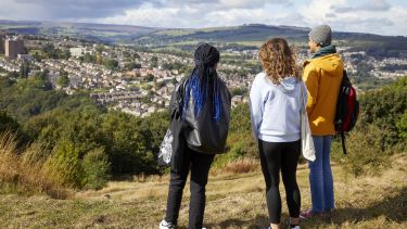 Three students looking out over the city of Sheffield from Crookes