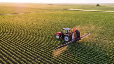 A tractor spraying pesticides in a field