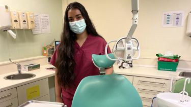 Dentistry female student with mask stands behind dentist chair