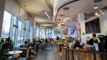 Photo of a cafe with people sat at tables and a wraparound counter