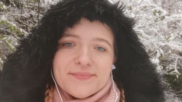 Catherine Newell in the snow with big furry hood and earplugs