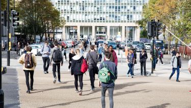 A photo showing a number of students crossing the road with the Arts Tower in the background.