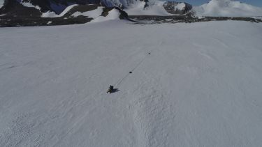 An aerial photo of Antarctica, showing a snowmobile with a radar survey attached to locate and examine subglacial lakes