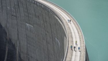 A image of a large dam. There are people walking along the top of it.
