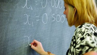 Photo of a teacher writing mathematical terms on a blackboard