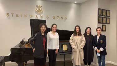 students at steinway showroom with pianist in front of piano