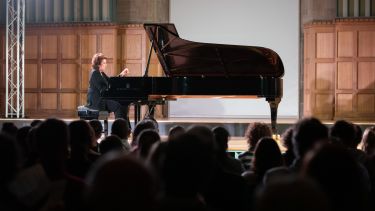 Dame Imogen Cooper playing Steinway piano in hall with audience 