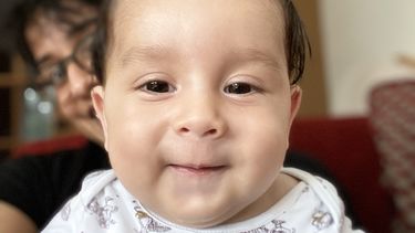 Picture of baby Sebastian who has SMA with her mother behind him