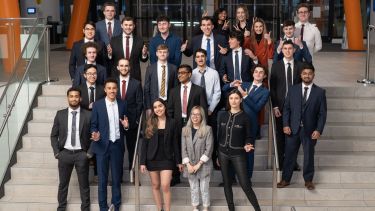 A group of students stood on steps in suits, who part of the Twikker Fund and USIS Society