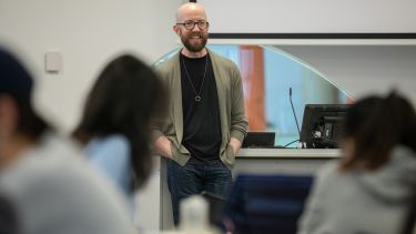 teacher stood at front of class smiling