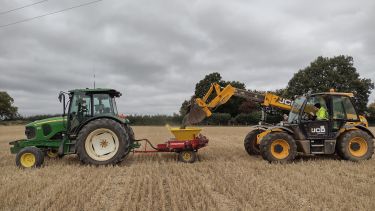 A tractor for spreading receiving crushed basalt from a front-loader at our field site in Harpenden