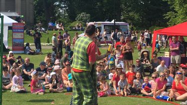 Families sat on the grass in Weston Park watching an entertainer at the last May Fayre in 2019