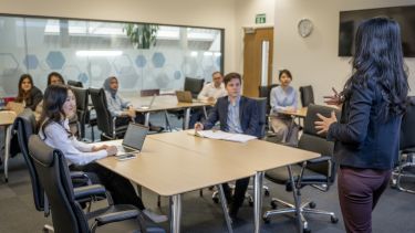 A group of students in a seminar room listening to a lecturer.