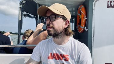 Philip sat on a boat with cap and glasses