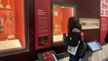 Photograph of Xhuljana in a museum in Sheffield looking at a display of history cutlery