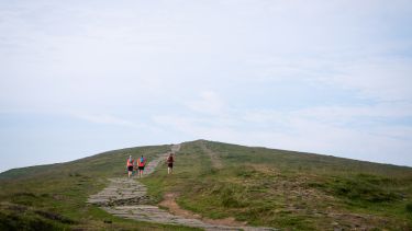 A photo showing three walkers climbing Mam Tor