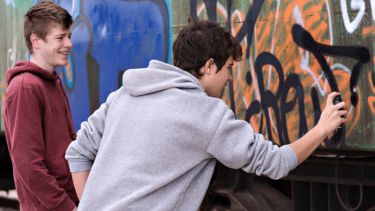 Teenagers graffiti on a wall