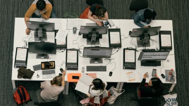 A birds eye view shot of students sat round a table of computers.