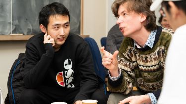 A student sits at a table in conversation with Dr Fionntan Roukema