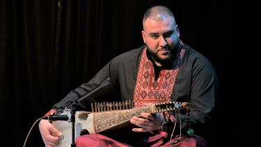 Rubāb player Saphwat Simab performing on stage.