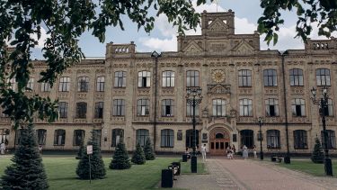 A grand building at the KPI campus in Kyiv, before the war, with people walking in the gardens