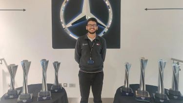 Photo of student Shamoil Khomosi at Mercedes surrounded by trophies