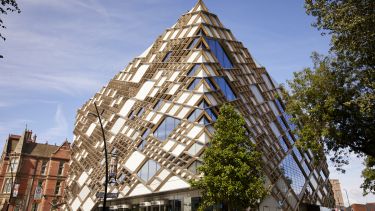 Exterior image of the diamond, a large white and gold building with geometric shapes on the outside