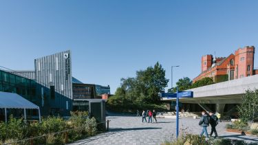 Students walking on the concourse with the University of Sheffield's Students' Union and Firth Court buildings on either side