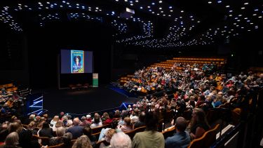 A large crowd facing a stage at a previous Off The Shelf event