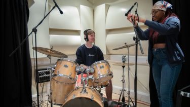 pair of students setting up drum kit in studio
